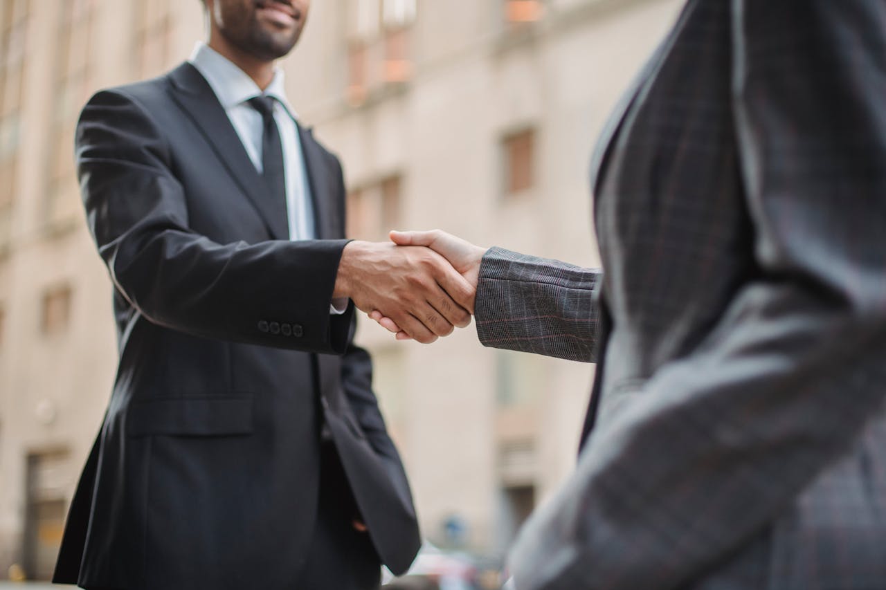 our-mission Business professionals greeting each other with a handshake outdoors, symbolizing partnership.