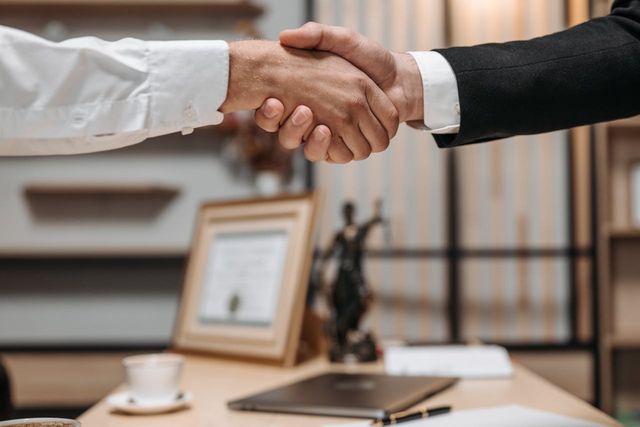 service-06 Close-up of a handshake between two professionals in a modern office setting, emphasizing partnership and agreement.